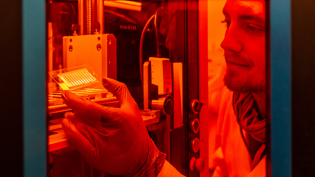 Laser pulses are used to structure the gold layer into conductive patterns. Lukas Hiendlmeier removes the structured samples from the laser system and examines them. Image: Andreas Heddergott / TUM