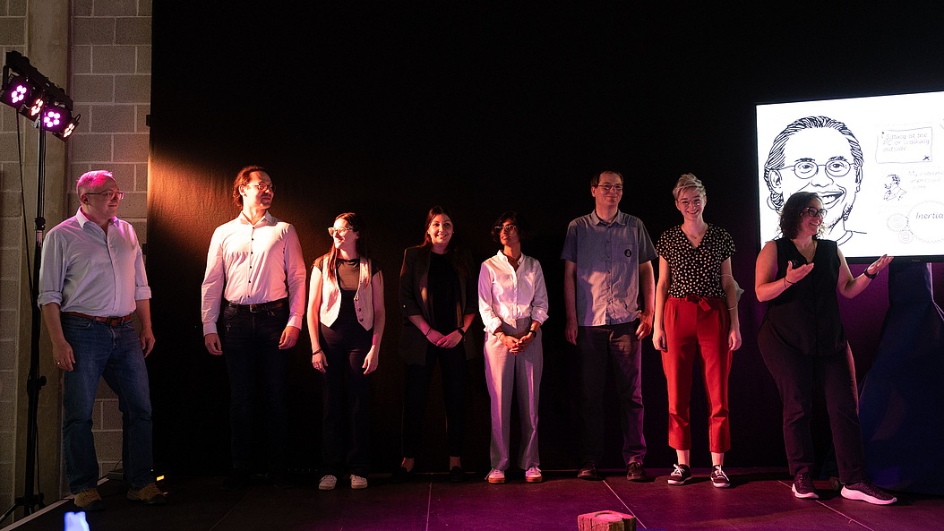 All eight MIBE slammers introduce themselves at the beginning of the event. From left to right: Prof. Oliver Hayden, Albert Croner, Patricia Capsi-Morales, Prof. Cristina Piazza, Prachi Kumari, Dr. Martin Dierolf, Franziska Hinterdobler, Prof. Berna Özkale Edelmann. Image: Carolin Lerch / TUM