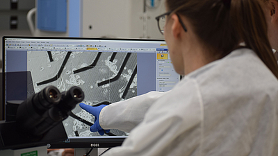 Checking the cells on multi-electrode arrays under the microscope at the Space Station Processing Facility at Kennedy Space Center. 