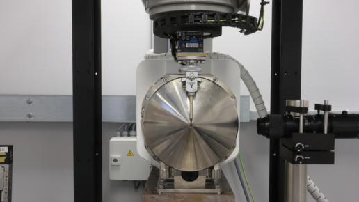Blick vom Detektor (nicht zu sehen) auf die Röntgenröhre gegen die Röntgenstrahlrichtung am nanoCT. Eine hängende Probe befindet sich sehr nah am Fokus der Röhre. Das Mikroskop rechts hilft bei der genauen Positionierung der Probe. Bild: Klaus Achterhold (TUM)