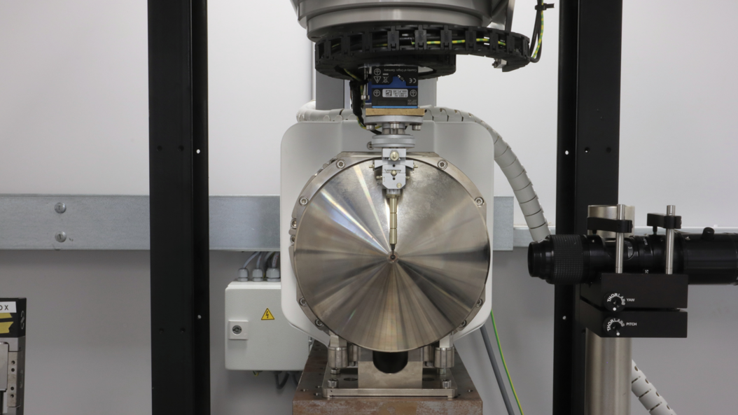 View from the detector (not visible) onto the X-ray tube, counter directed to the beam direction at the nanoCT. A sample is situated very close to the focal spot of the tube. The microscope to the right can be used to help position the sample with high precision.   Image: Klaus Achterhold / TUM