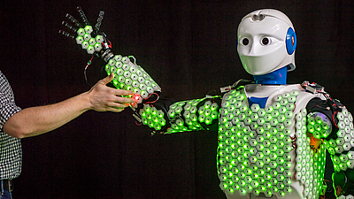 Humanoid robot covered with artificial skin encounters a human.